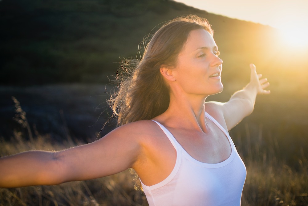 Beautiful young woman stretching her arms joyfully praising the beauty of Life.